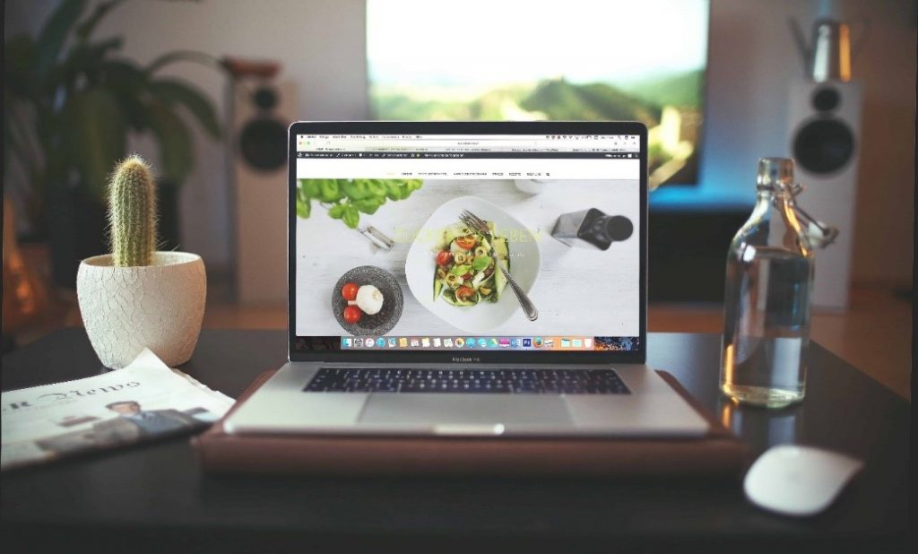 A laptop sitting on a wooden desk, open on a static web page.